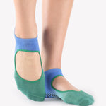 Woman wearing a blue to green ombre strap grip sock, made for pilates, barre, yoga, and beyond. 