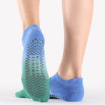 Woman wearing a blue to green ombre strap grip sock, made for pilates, barre, yoga, and beyond. 