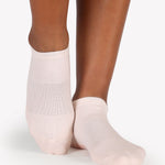 Women wearing a solid light baby pink full foot grip sock made for Pilates, Barre, Yoga, and beyond. 