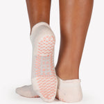 Women wearing a solid light baby pink full foot grip sock made for Pilates, Barre, Yoga, and beyond. 