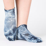 Woman wearing a dark blue full foot grip sock with it tie dyed white, made for pilates, barre, yoga, and beyond.  