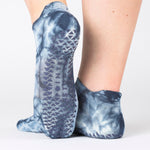 Woman wearing a dark blue full foot grip sock with it tie dyed white, made for pilates, barre, yoga, and beyond.  