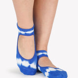 A close up photo of a woman's feet wearing blue and white tie-dye socks with a strap