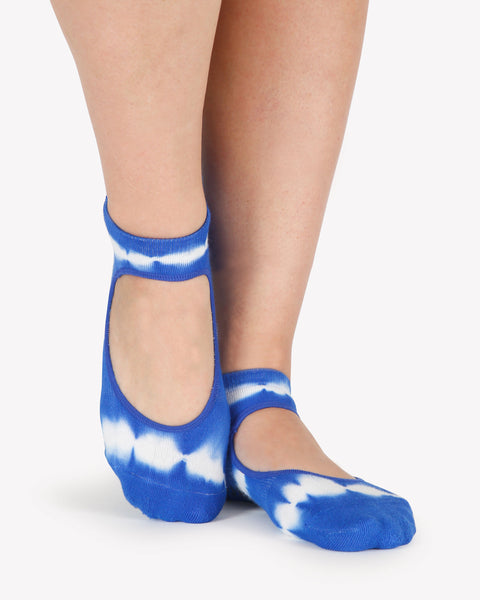 A close up photo of a woman's feet wearing blue and white tie-dye socks with a strap