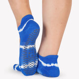 A close up photo of a woman's feet wearing blue and white tie-dye socks with grip