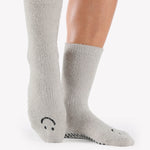 Women wearing grey fuzzy plush crew grip socks with a black happy face for recovery and relaxing.  