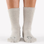 Women wearing grey fuzzy plush crew grip socks with a black happy face for recovery and relaxing.  