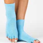 Woman wearing a solid light blue toeless ankle grip sock, made for pilates, barre, yoga, and beyond.