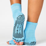 Woman wearing a solid light blue toeless ankle grip sock, made for pilates, barre, yoga, and beyond.