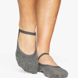 A close up photo of a woman's feet wearing grey socks with a strap