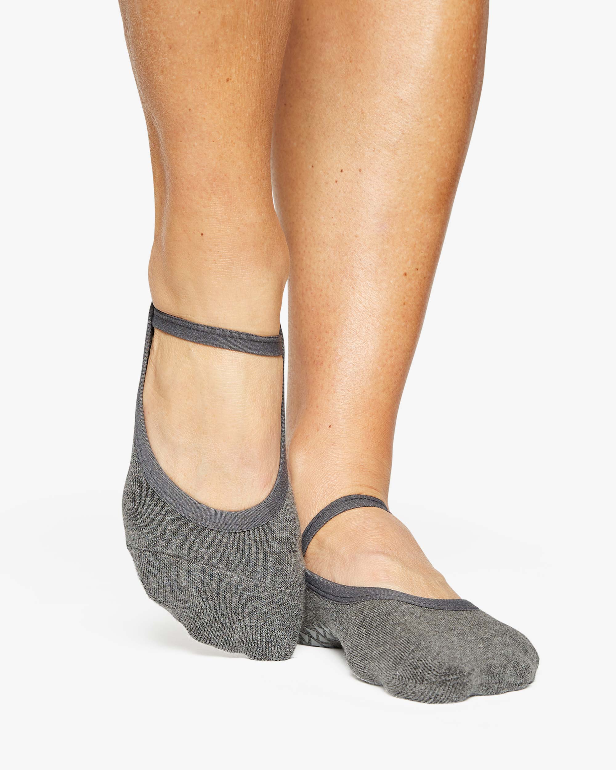 A close up photo of a woman's feet wearing grey socks with a strap