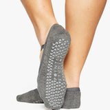 A close up photo of a woman's feet wearing grey socks with grip