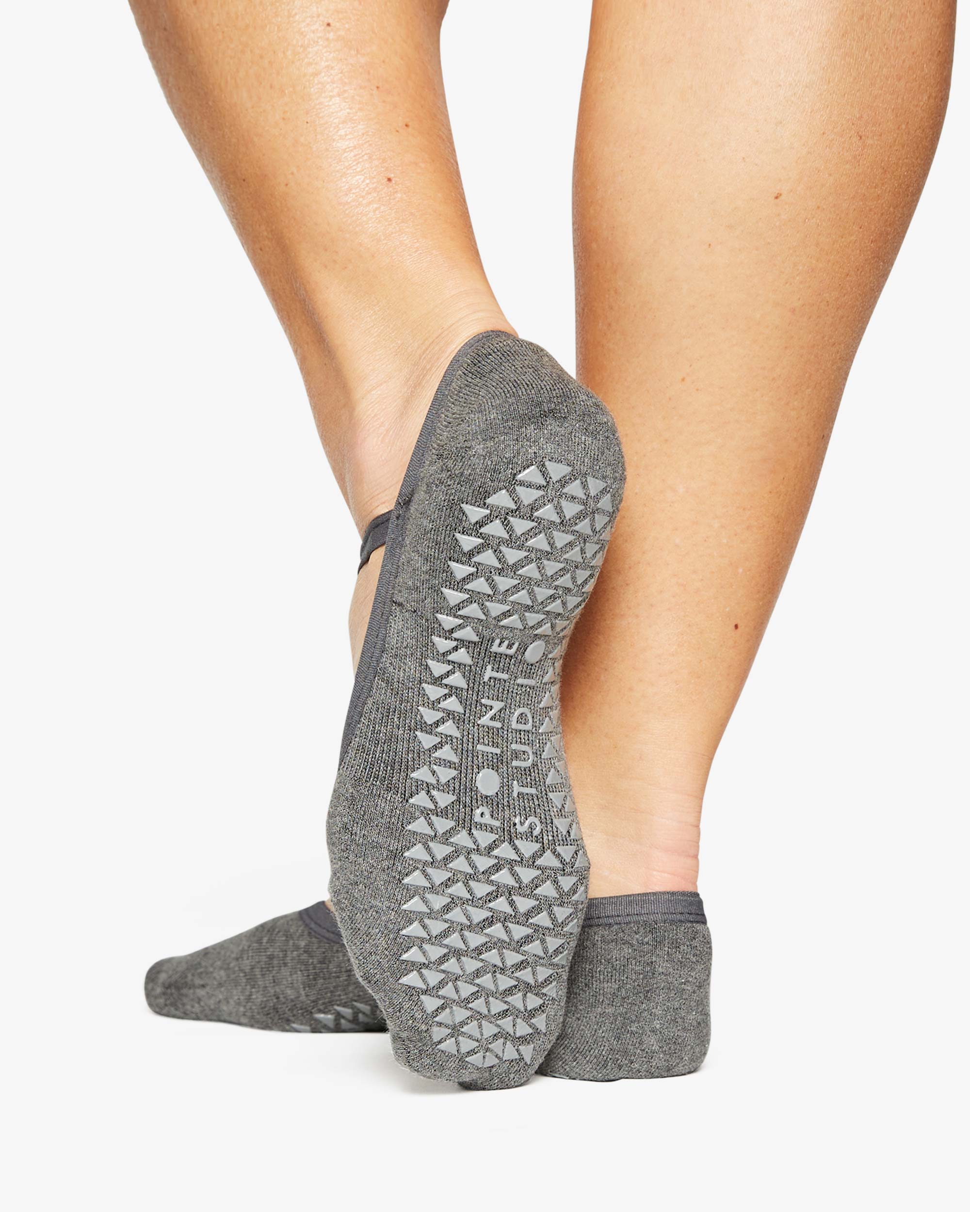 A close up photo of a woman's feet wearing grey socks with grip