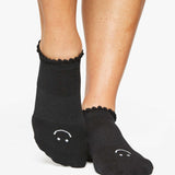 Close up photo of a woman's feet wearing black socks with a happy face on the top of the foot