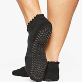 Close up photo of a woman's feet wearing black socks with grip of the bottom of the foot