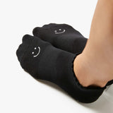 Close up photo of a woman's feet wearing black socks with a happy face on the top of the foot