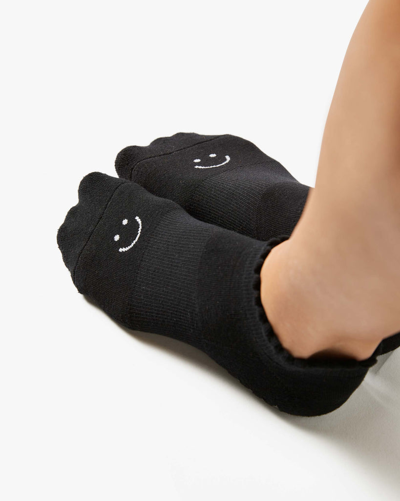 Close up photo of a woman's feet wearing black socks with a happy face on the top of the foot